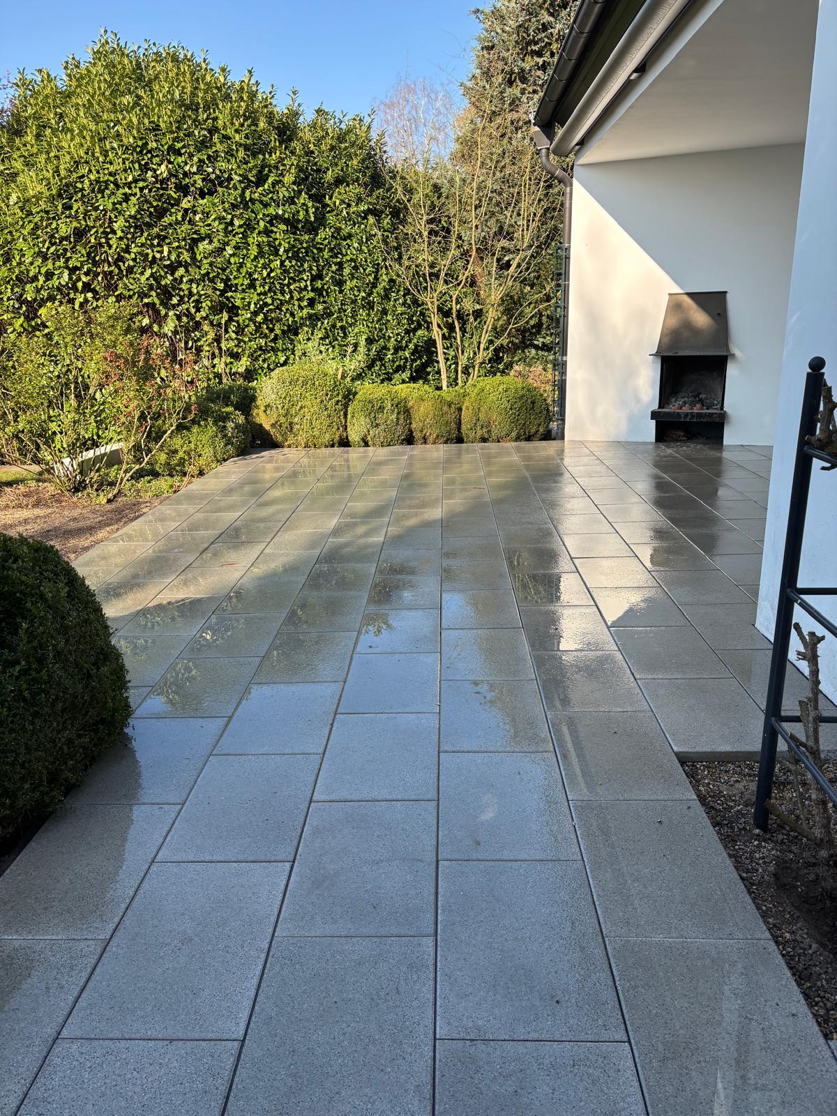 Fertige Granitterrasse mit Außenkamin und Heckenrahmen